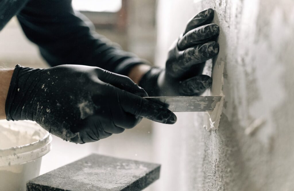 Trade student sanding and filling a plasterboard wall in preparation for painting